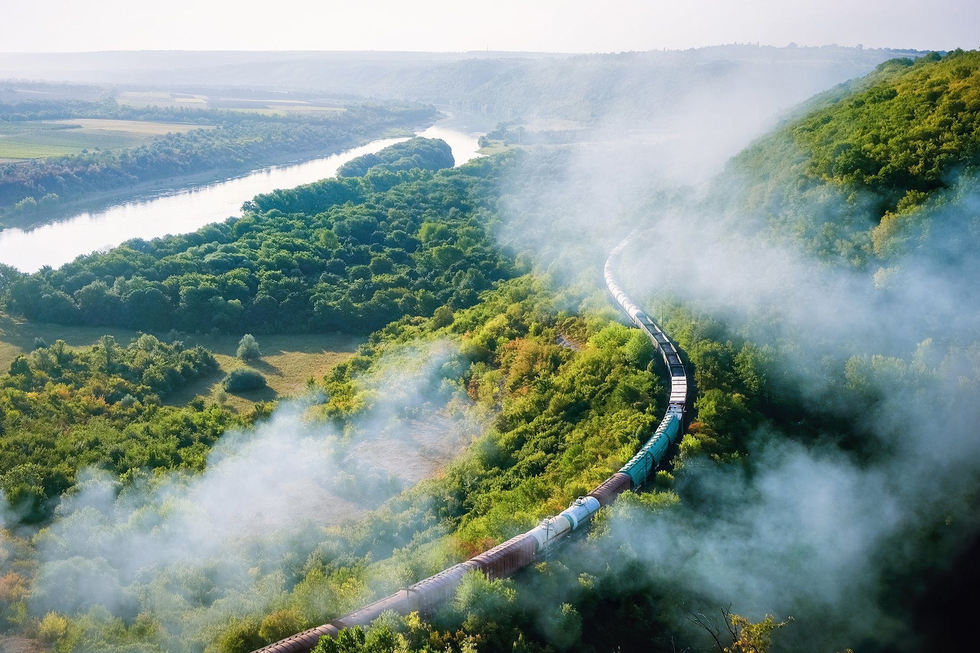 moving train railway with high column smoke flowing river hills railway foreground